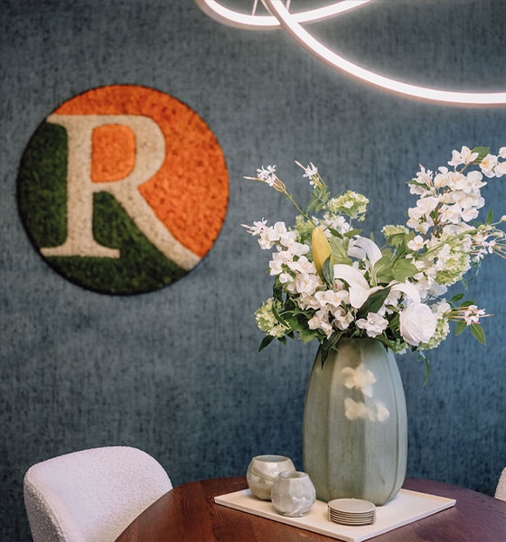 Het logo van Regio Makelaars naast een vaas met bloemen op tafel