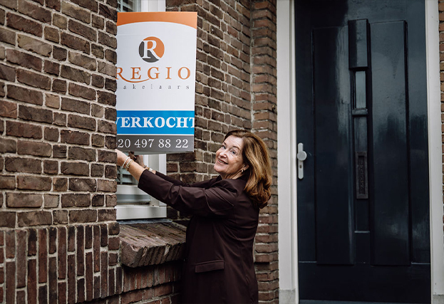 makelaar hangt verkoopbord op