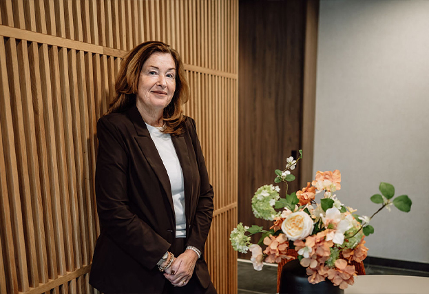 angelique tegen muur in kantoor naast bloemstuk