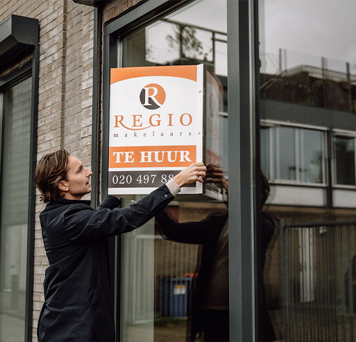 makelaar hangt huur bord op woning